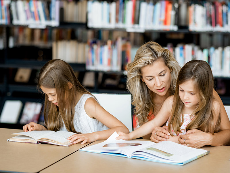 Madre con hijas haciendo tarea escolar